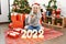 Young beautiful woman with white modern hair standing by christmas tree celebrating 2022 new year annoyed and frustrated shouting