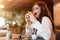 Young beautiful woman in white stylish blouse looks hungry eating meat burger with fries for lunch in trendy cafe eating outside