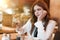 Young beautiful woman in white stylish blouse looks hungry looking at fresh meat burger during lunch in trendy cafe eating outside