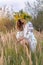 Young beautiful woman in a wreath of wildflowers and ancient national clothes gathers spikelets in a meadow of yellow