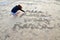 Young beautiful woman writting into a sand on the beach