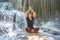 Young beautiful women doing yoga sitting pose at waterfall