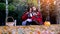 Young beautiful women sitting on picnic bundled up in a blanket drinking hot tea from thermos in autumn park. Girls rug