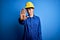 Young beautiful worker woman with blue eyes wearing security helmet and uniform doing stop sing with palm of the hand