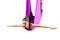 Young beautiful yogi woman doing aerial yoga practice in purple hammock.