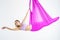 Young beautiful yogi woman doing aerial yoga practice in purple hammock