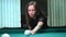 Young beautiful young lady aiming to take the snooker shot while leaning over the table in a club