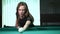 Young beautiful young lady aiming to take the snooker shot while leaning over the table in a club