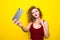 Young beautifulgirl with an curly hairstyle send selfie kiss. Laughing girl take selfie from phone on Yellow background.
