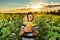 A young beekeeper with a jar of honey among a field of sunflowers advertises honey