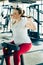 Young beginner girl exercising in the fitness gym, with lat machine