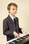 Young beginner musician in suit playing the digital piano
