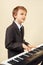 Young beginner musician in suit playing the electronic synthesizer