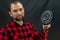 A young bicycle mechanic in a red plaid shirt with bicycle parts in his hands stands on a black background. The new crankset is in