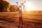 Young bicyclist raising her bicycle in autumn field. Happy woman celebrates success holding bike in hands