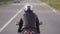 A young biker in a leather jacket and a helmet riding at the motorcycle along the highway around the city. Close-up