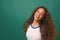 Young biracial woman dancing flipping hair, green studio background