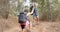 Young biracial woman helps her friend up a steep trail during a hike