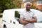 Young black adult tradesman standing next to his white van, close up, close up