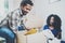 Young black american african couple with moving boxes in new apartment.Cheerful couple sitting in empty new house