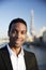 Young black businessman in smart casual clothing standing by the River Thames in London smiling to camera, close up