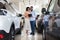 Young Black Couple Choosing Car In Modern Dealership Center, Checking Vehicle Characteristics