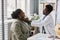 Young black doctor palpating neck examining woman in clinic