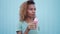 Young black girl eating pink melting ice cream at blue wall background