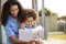 Young black girl reading book sitting on mumï¿½s knee outdoors