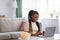 Young black lady choosing movie on laptop