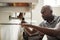 Young black male plumber sitting on the floor fixing a bathroom sink, close up