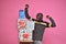 young black man feeling excited and happy and delighted, celebrating while standing next to a stack of gift boxes with fists in