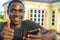 young black man holding his mobile phone smiling and giving a thumbs up