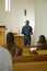 Young black man in shirt with clerical collar and pants preaching in church