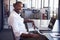 Young black man sitting at desk in office smiling to camera