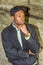 Young black man standing outdoors by rocks in park in rainy day in New York City