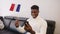 Young black man watching game play on smartphone and waving flag of France