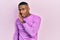 Young black man wearing casual pink sweater hand on mouth telling secret rumor, whispering malicious talk conversation