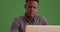 Young black man working on a laptop on green screen