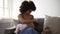 Young black mother breastfeeding newborn in living room Spbd. Happy 20s mixed african woman smiles