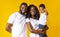 Young black parents with adorable infant son over yellow background