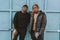 Young Black Spanish male friends standing in front of a blue metal gate