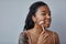 Young black woman with acne scars and tattoos using face massager