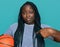 Young black woman with braids holding basketball ball pointing finger to one self smiling happy and proud