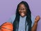 Young black woman with braids holding basketball ball screaming proud, celebrating victory and success very excited with raised