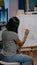 Young black woman drawing vase on white canvas in art studio