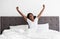 Young black woman enjoying happy morning, stretching in bed