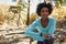 Young black woman in a forest checking smartwatch looks away