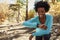 Young black woman in a forest checking smartwatch and smiling