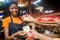 Young black woman selling food stuff in a local african market collecting money from a paying customer